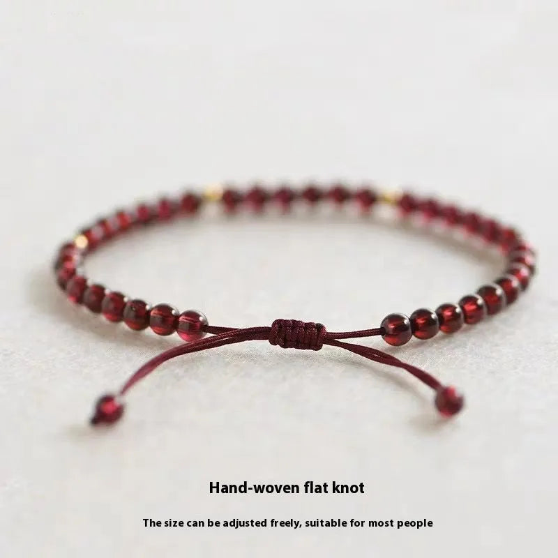 Hand-woven garnet red rope bracelet with flexible wire on a neutral background.
