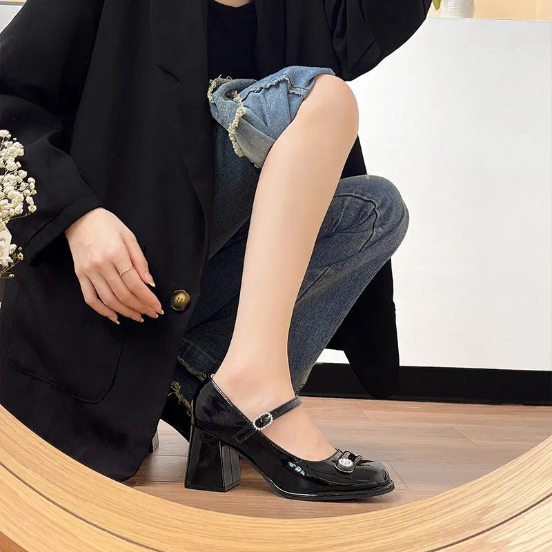 Women's black patent leather chunky heel court shoes with round toe and buckle fastening.