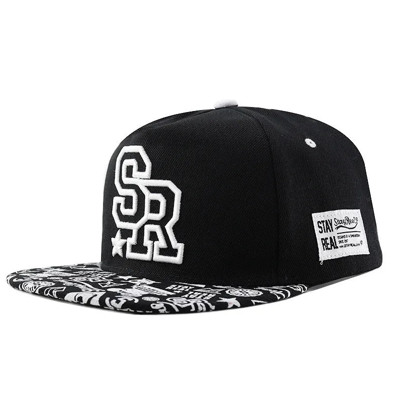 Cotton baseball cap with embroidered letters in black or white, showing adjustable strap and dome crown.