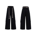 Men's dark blue straight-leg jeans with heavy 3D cutting, belt stitching, and tassel details on a loose fit.
