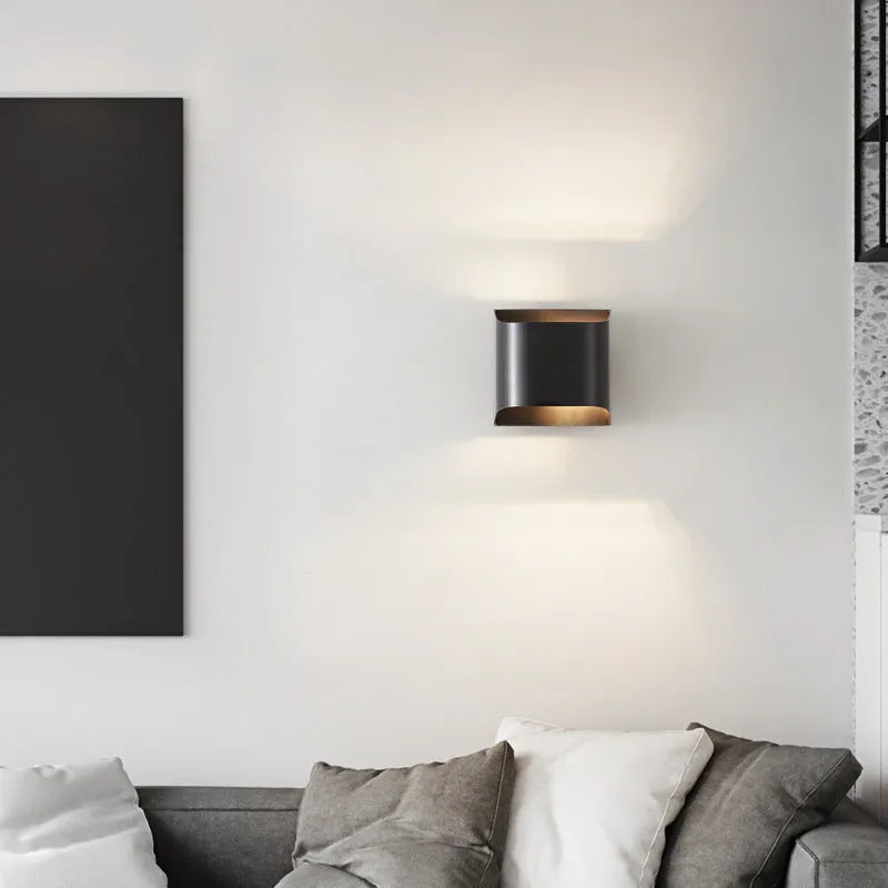 Minimalist copper wall lamp in black gold finish mounted beside a bed