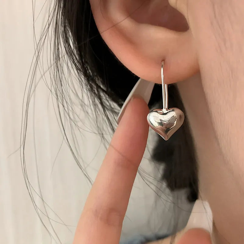 Silver coloured heart-shaped earrings with three-dimensional glossy finish and Korean style design