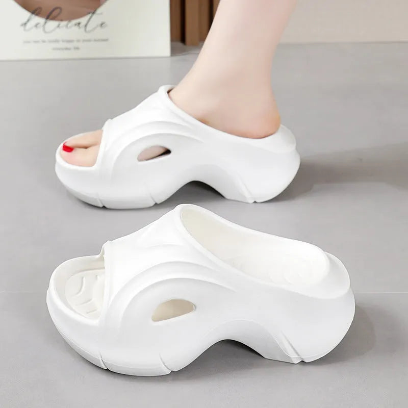 Women's white thick-soled EVA slippers on a sandy beach background.