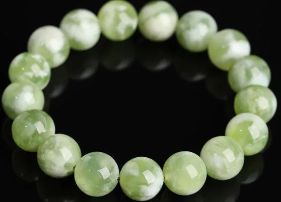 Polished green milk-in-water Xiuyan jade bracelet showing single circle of beads on a wrist.