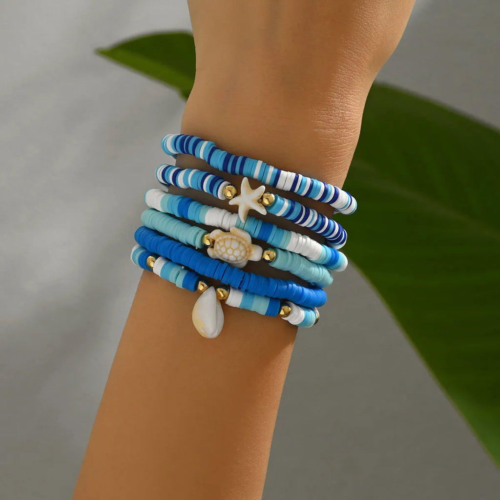 Six Bohemian blue polymer clay bracelets with geometric shell designs arranged as a set