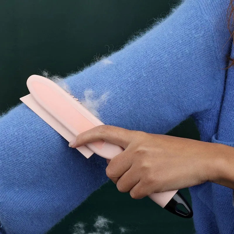 Pink and green handheld pet hair remover brush with grooming comb and integrated clothes hair collector.