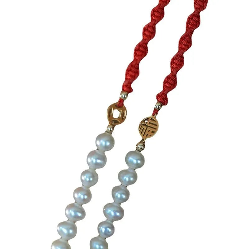Women's pearl bracelet with gold-plated fu charm on braided red rope