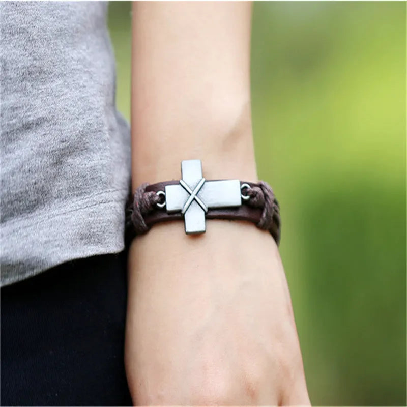 Brown leather cross bracelet with first layer cowhide and alloy accents on a neutral background
