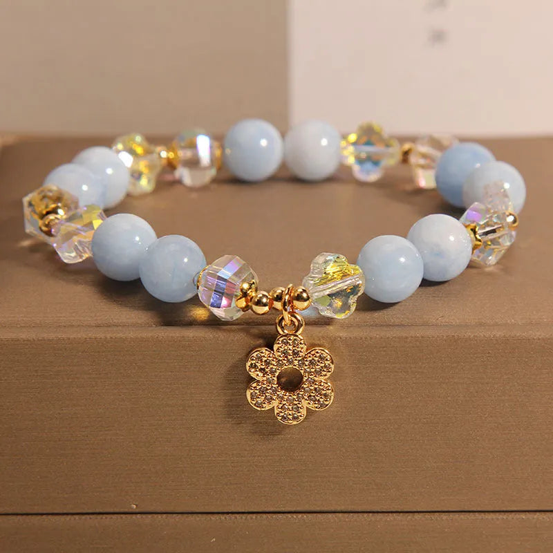 Women's aquamarine crystal bracelet with a four-leaf clover charm and pearl detail.