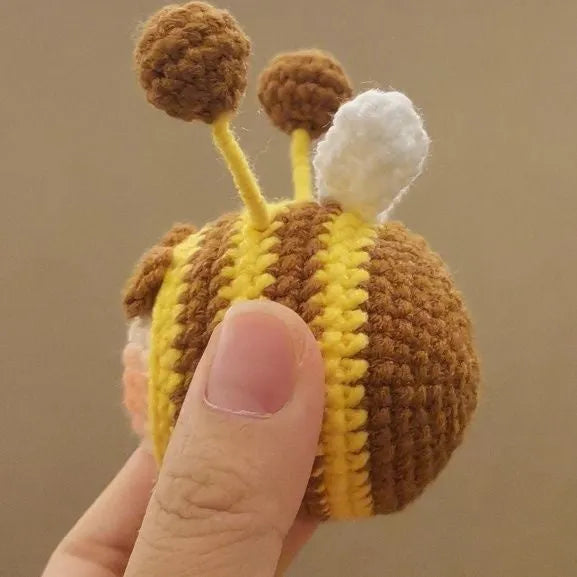 Handmade crocheted plush bee hive and bees accessory for woolen dolls on a white background.