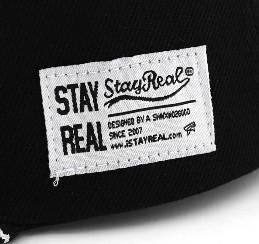 Cotton baseball cap with embroidered letters in black or white, showing adjustable strap and dome crown.