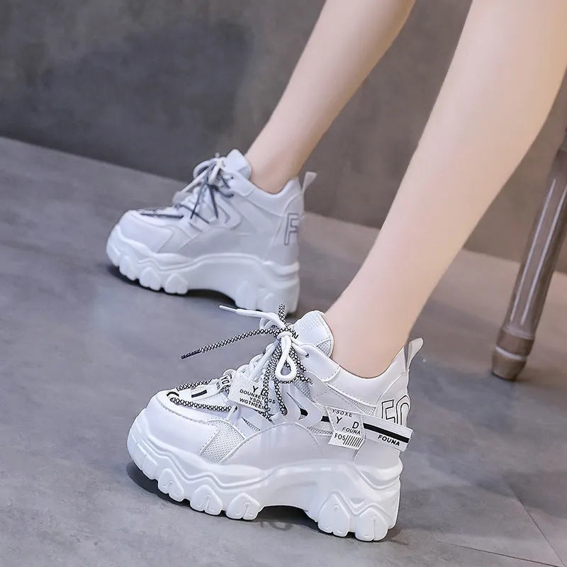 Women's white and black platform tennis shoes with mesh upper and cross-strap.