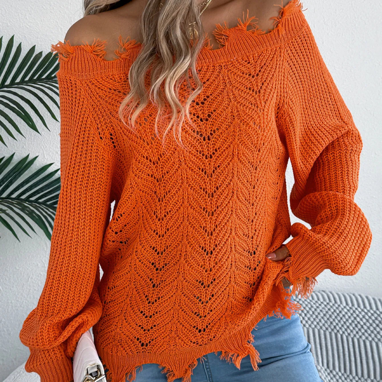 Women's white hollow-out off-the-shoulder long sleeve pullover sweater on a hanger.