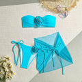 Women's pink tube top swimsuit with large 3D flower tie, matching pants, and skirt laid flat.
