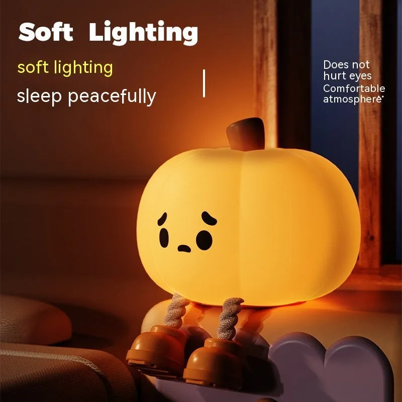 Soft orange silicone pumpkin-shaped night light with a warm glowing face on a table.