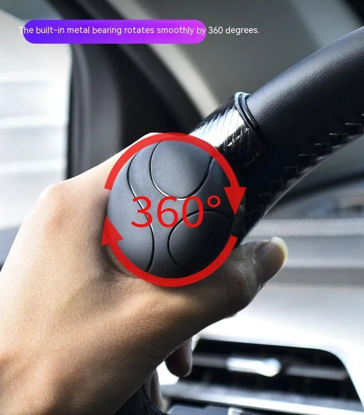 Black silicone steering wheel assist ball with metal bearing for single-handed driving aid.