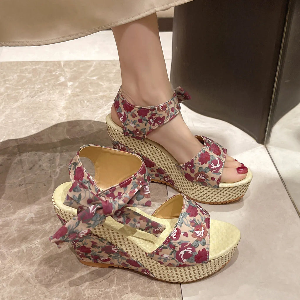 Women's pink floral peep toe wedge sandals with an ankle strap buckle on a rubber sole.