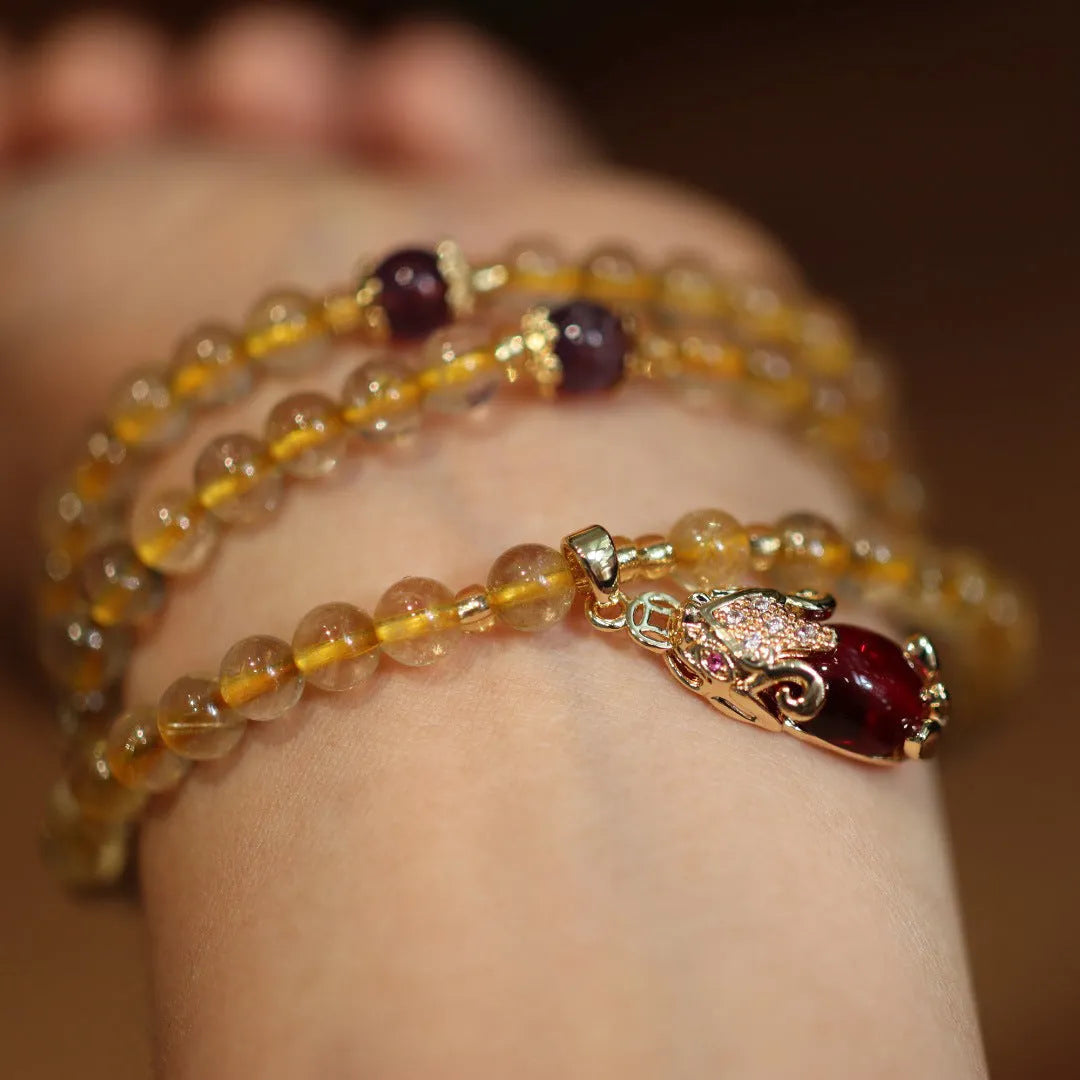 Handmade natural gold rutilated quartz bracelet with three gold circles and a chopsticks charm on a white background.