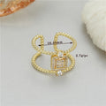 Gold-coloured asymmetric U-shaped open ring with an adjustable opening on a neutral background.