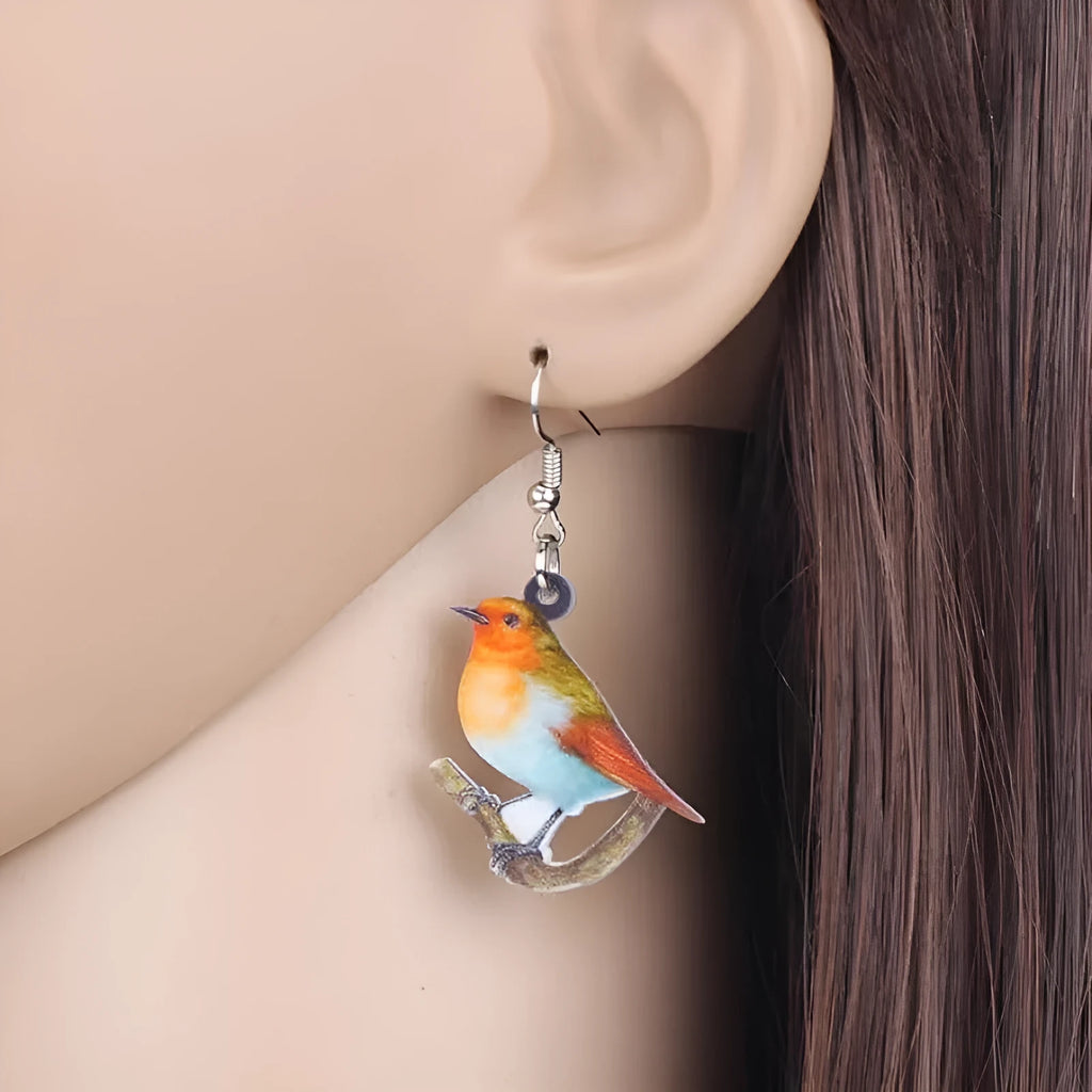 A pair of blue titmouse pendant earrings with printed design on acrylic, featuring geometric and snake elements.