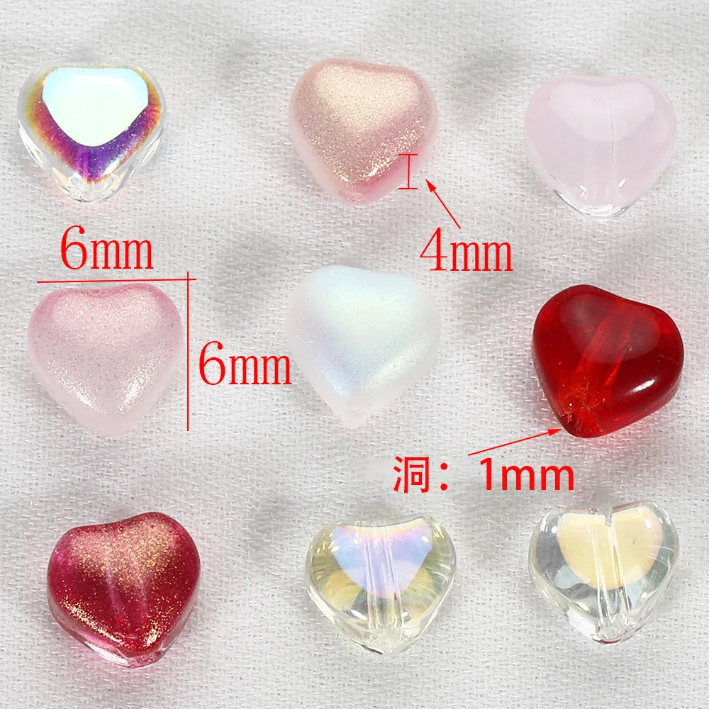 Twenty transparent love heart shaped spacer beads in assorted colours on a white background.