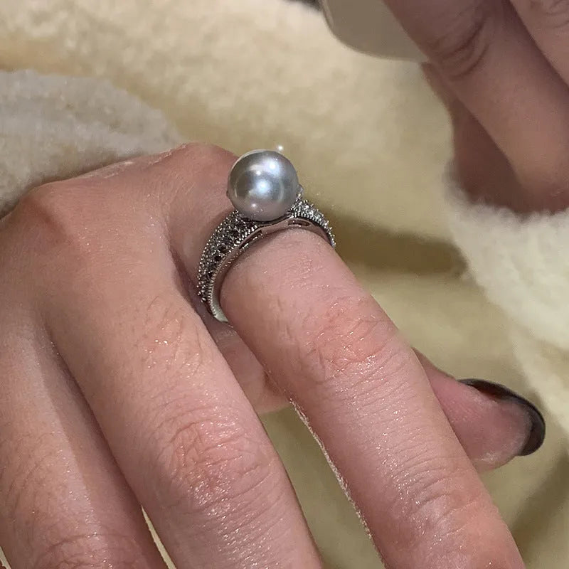 Geometric copper ring with black pearl and adjustable opening on a female index finger.