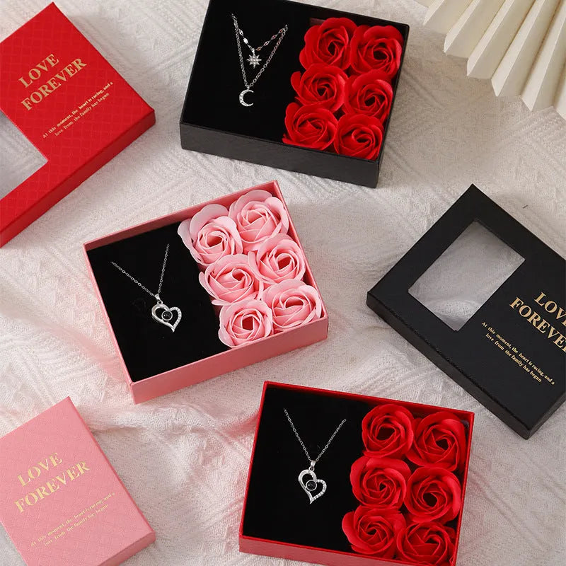 Red Korean-style jewellery gift box open to show six pink soap flowers, with a black handbag beside it.