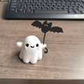 Small resin statue of an American-style ghost walking a dog and holding a bat.