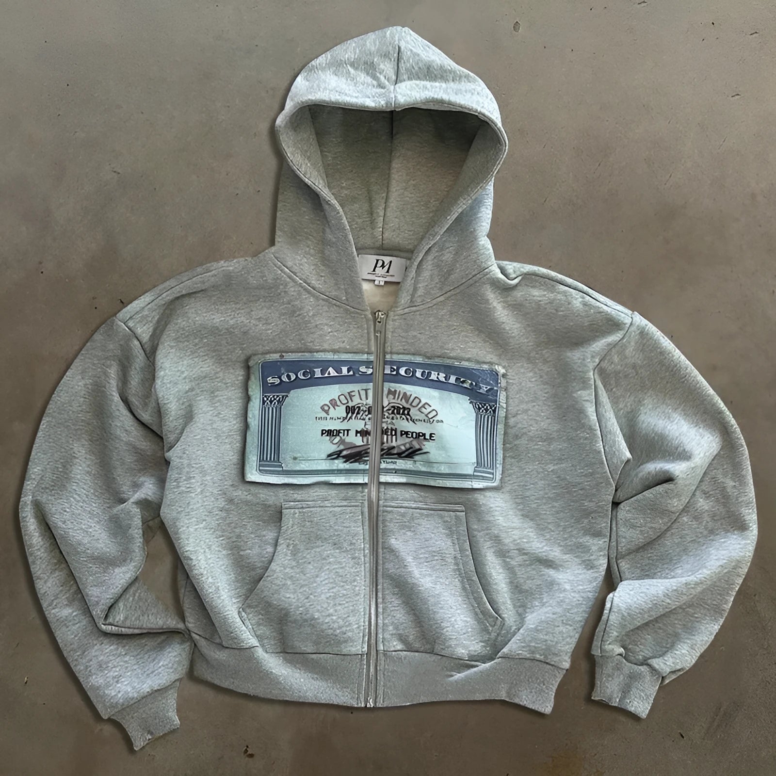 A loose-fitting unisex hoodie jacket with a front zipper, hood, and zip pockets, featuring a letter print.