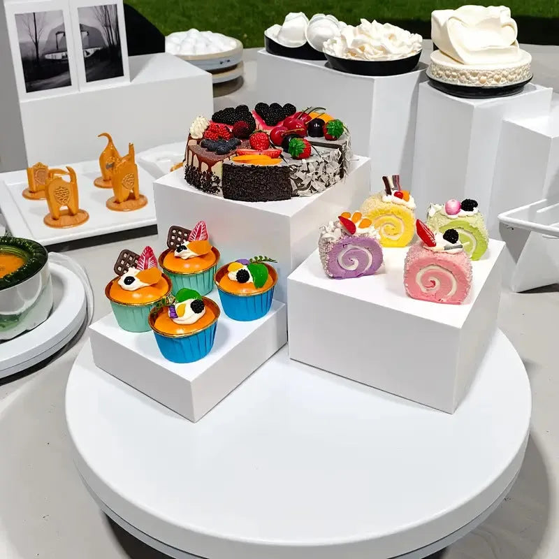 White and transparent plastic suit cube dessert display stands arranged in a tiered formation.
