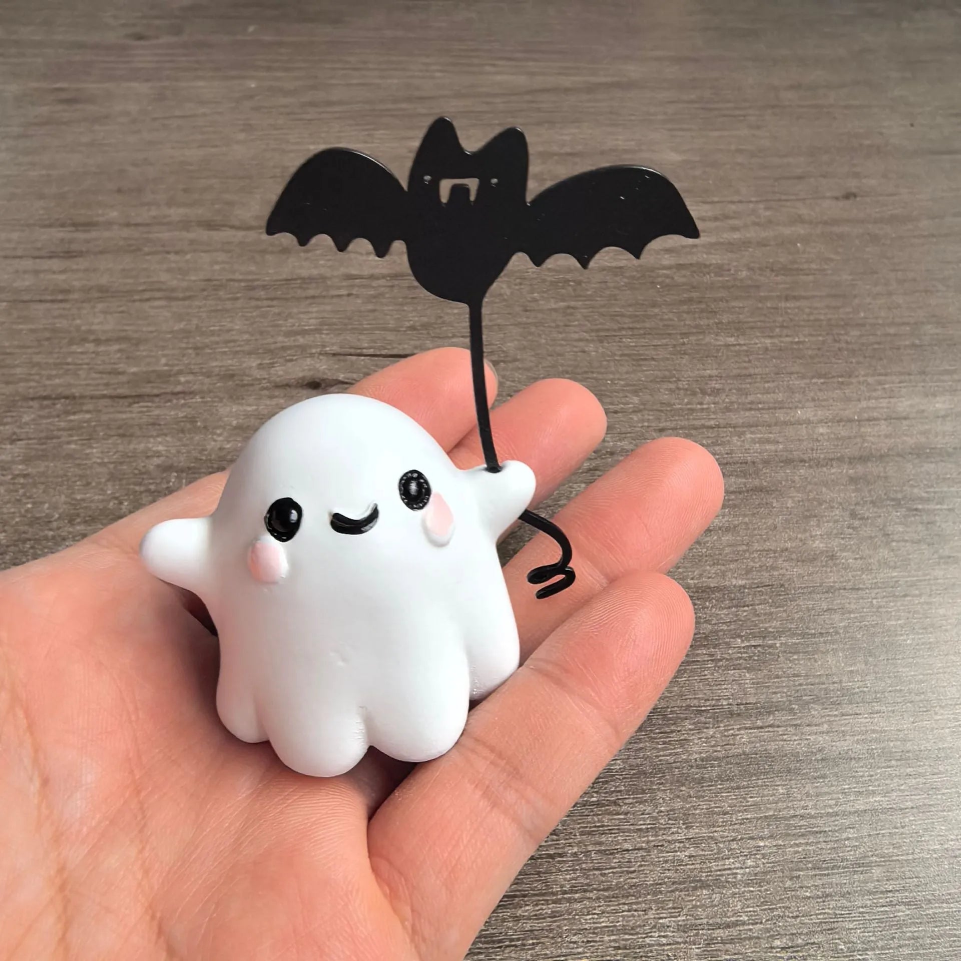 Small resin statue of an American-style ghost walking a dog and holding a bat.