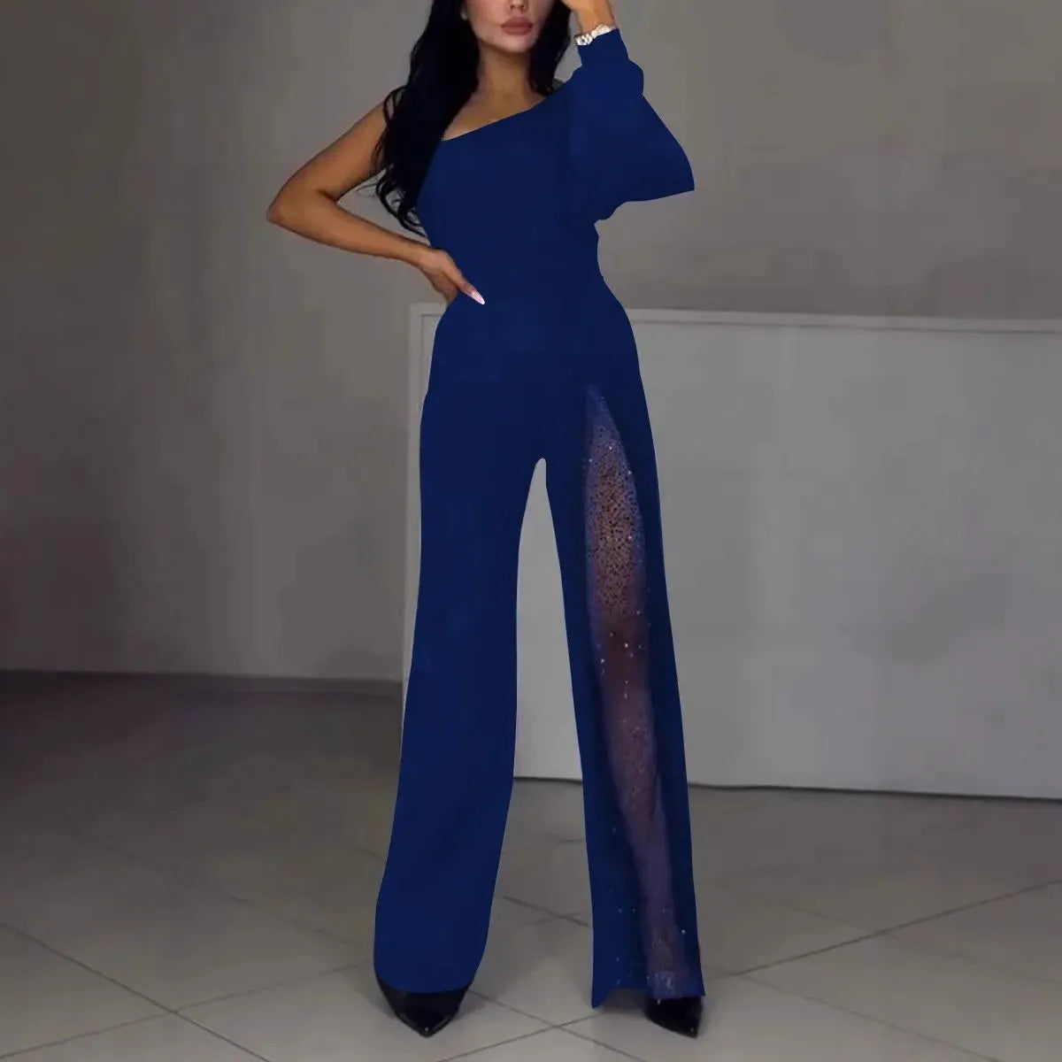 A woman modelling a black, long-sleeve polyester jumpsuit with a high leg slit and mid-waist design.