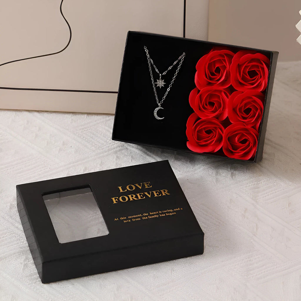 Red Korean-style jewellery gift box open to show six pink soap flowers, with a black handbag beside it.