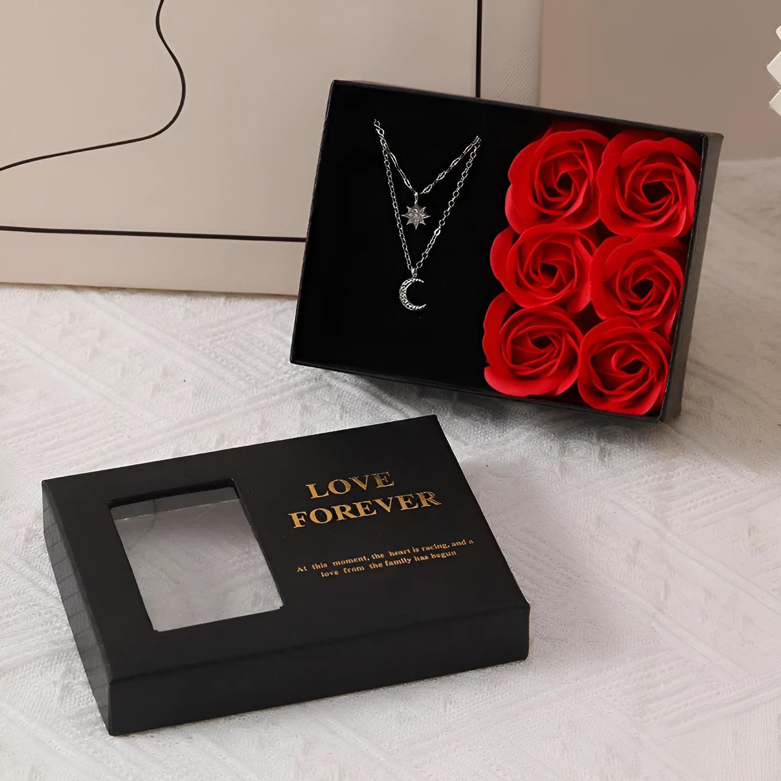 Red Korean-style jewellery gift box open to show six pink soap flowers, with a black handbag beside it.