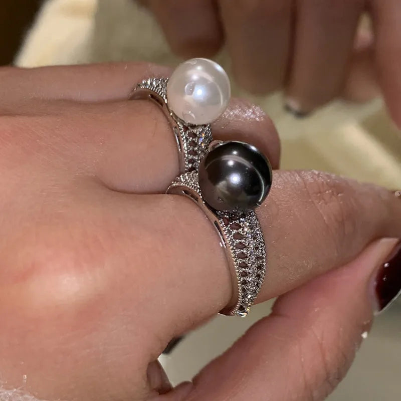 Geometric copper ring with black pearl and adjustable opening on a female index finger.