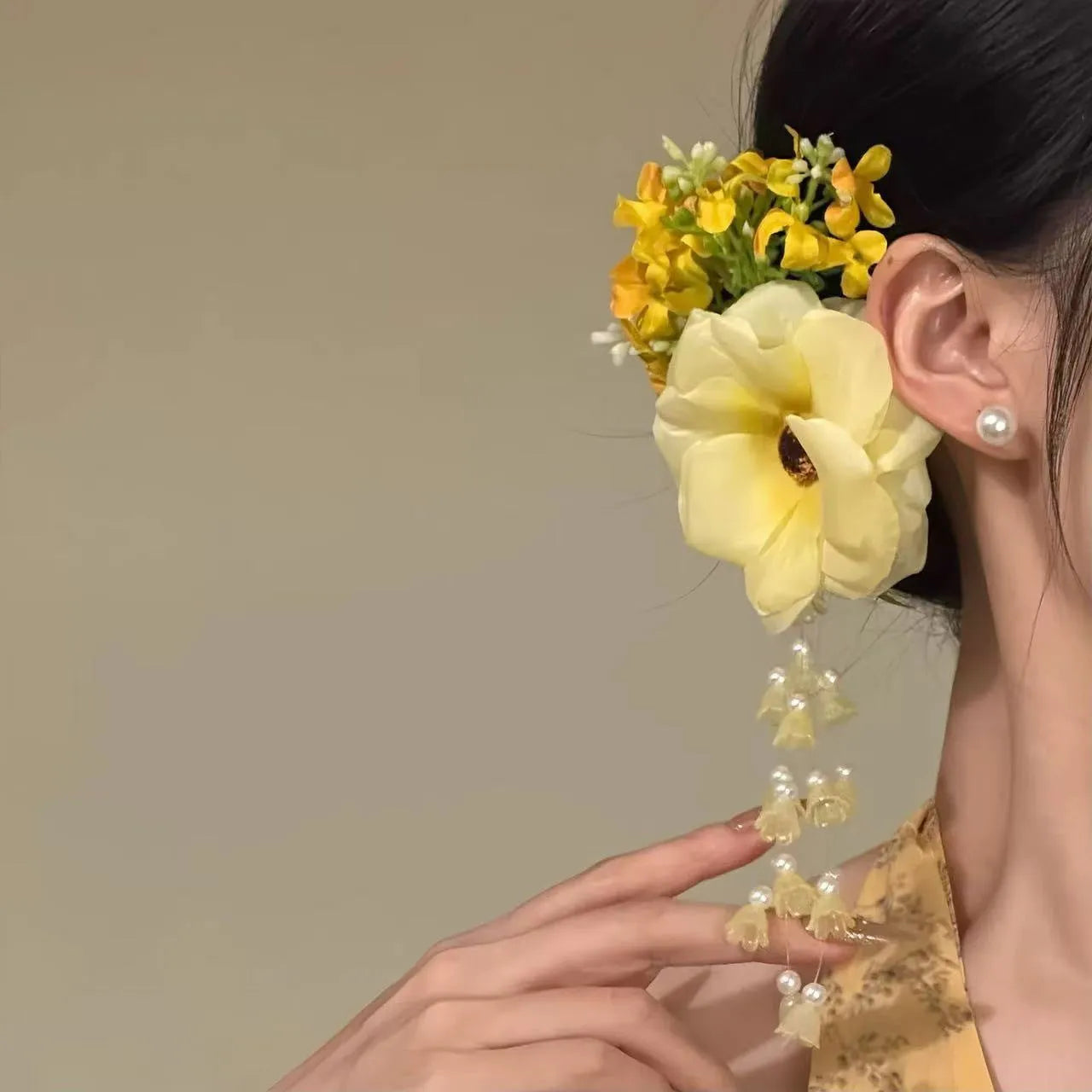 Yellow flower with tassel decorative side clip hair accessory on white background.