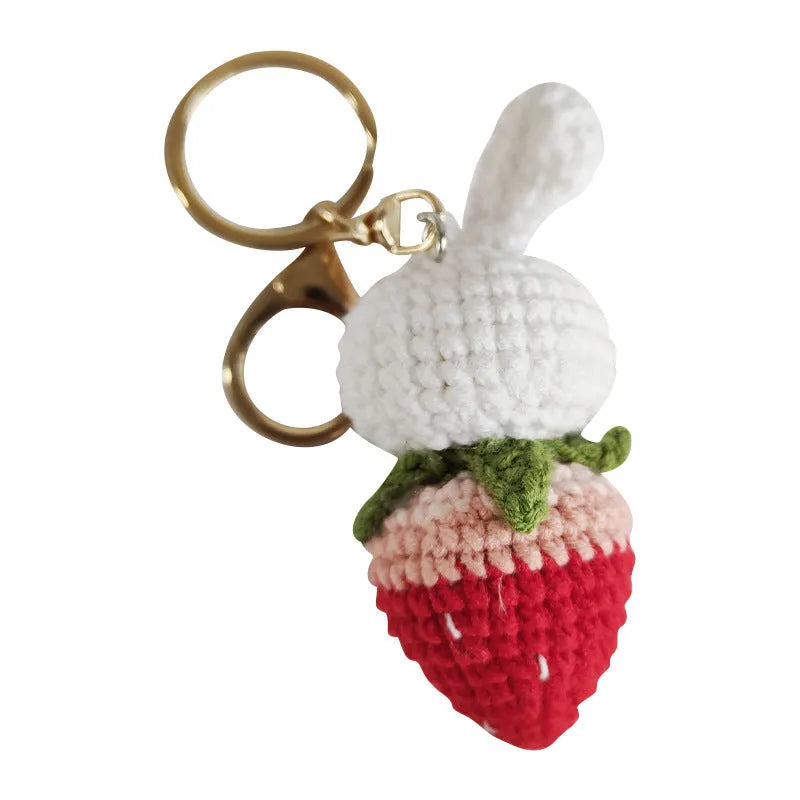 White hand-woven wire pendant showing a rabbit and strawberry design with an attached metal key.