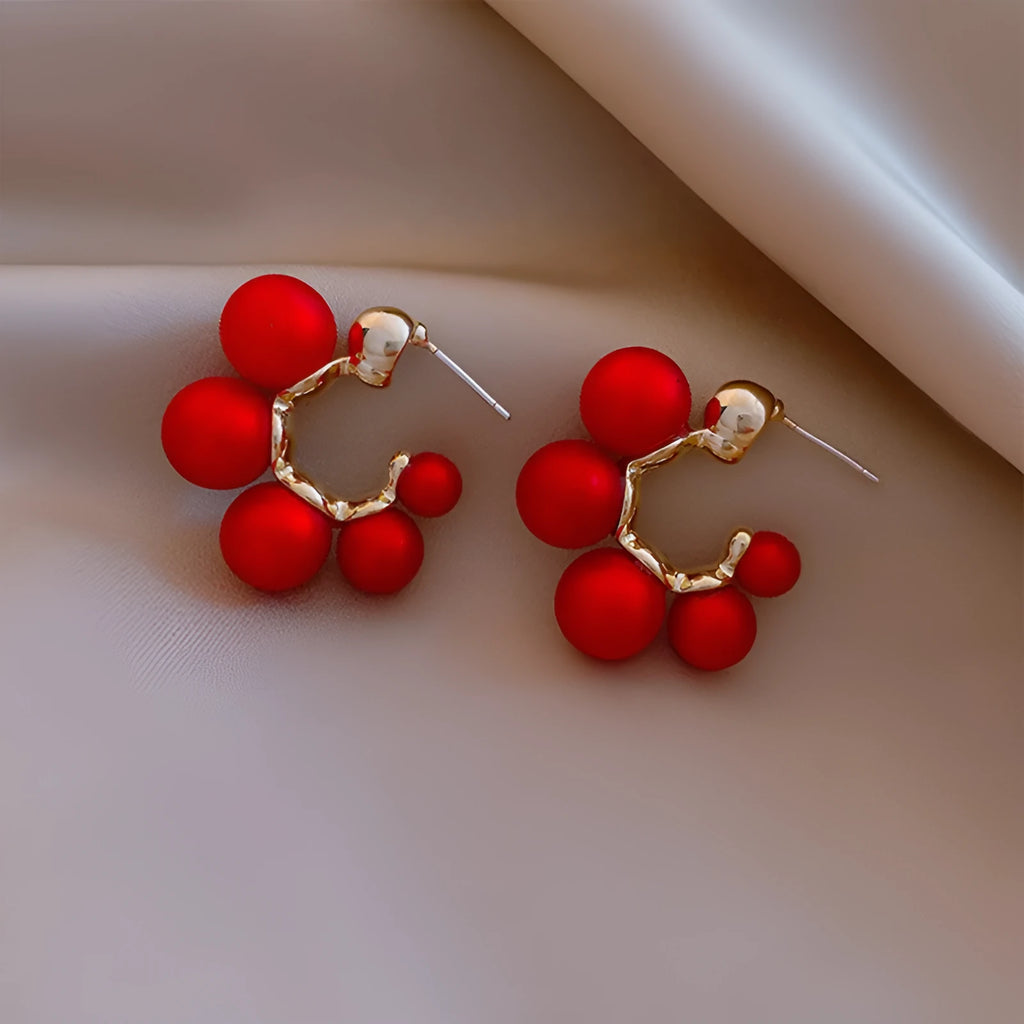 A pair of red bell-shaped alloy earrings for women on a plain background.