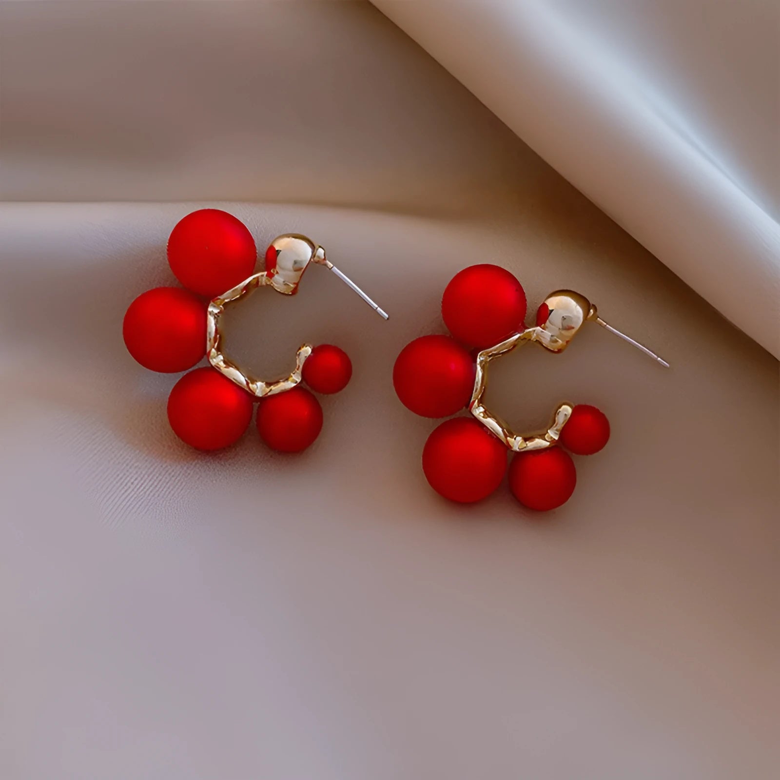 A pair of red bell-shaped alloy earrings for women on a plain background.