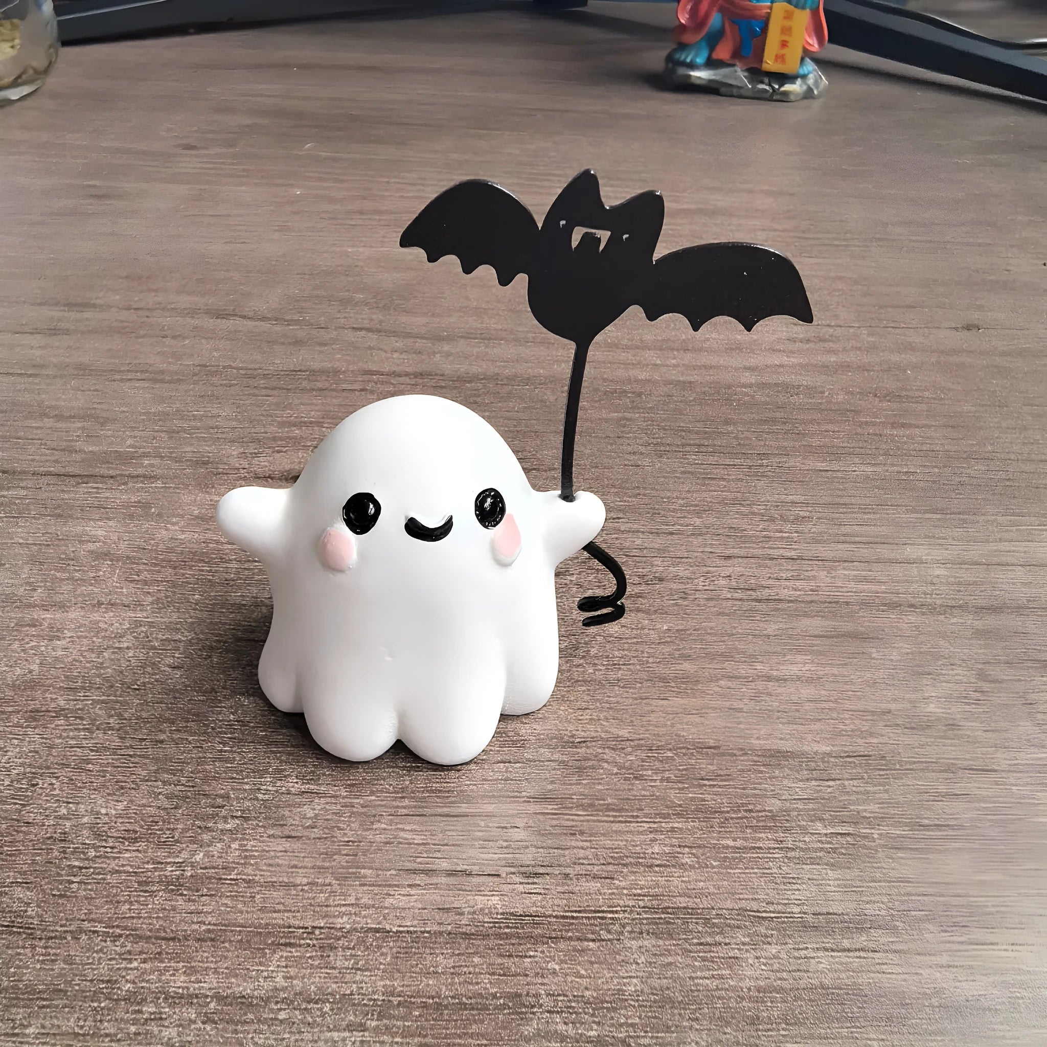 Small resin statue of an American-style ghost walking a dog and holding a bat.