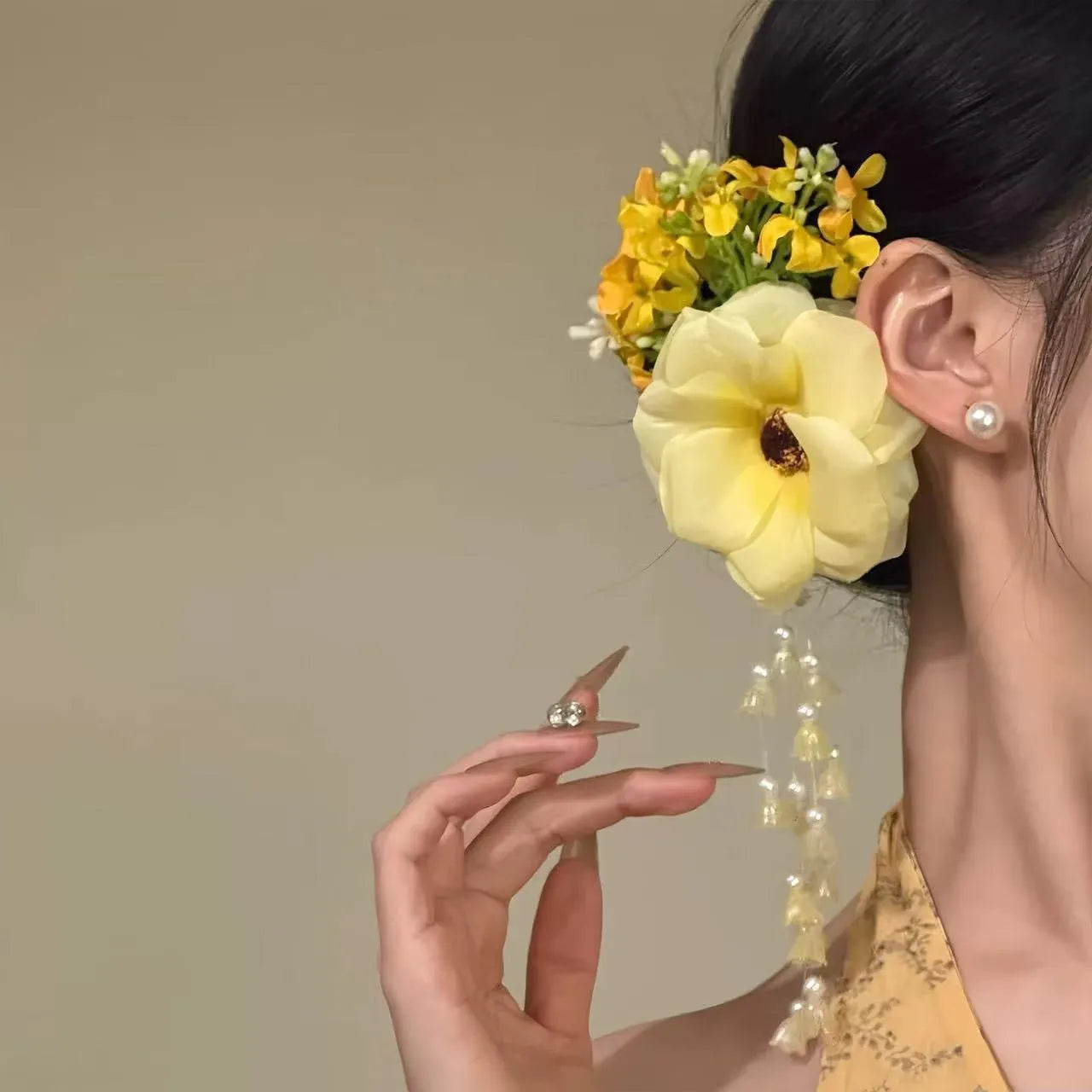 Yellow flower with tassel decorative side clip hair accessory on white background.