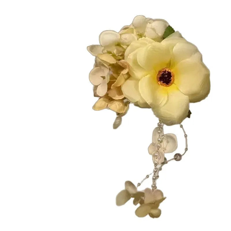 Yellow flower with tassel decorative side clip hair accessory on white background.