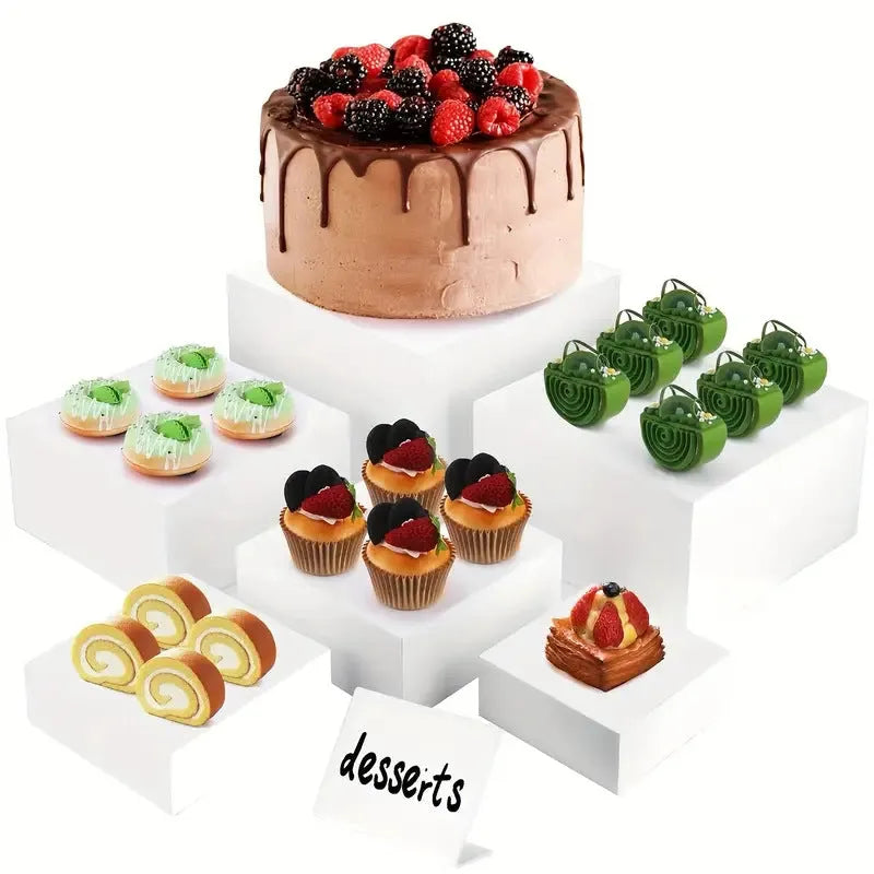 White and transparent plastic suit cube dessert display stands arranged in a tiered formation.