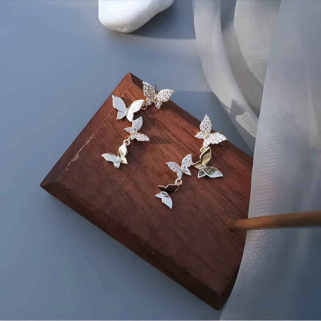 Gold-coloured copper butterfly drop earrings showing four butterfly designs