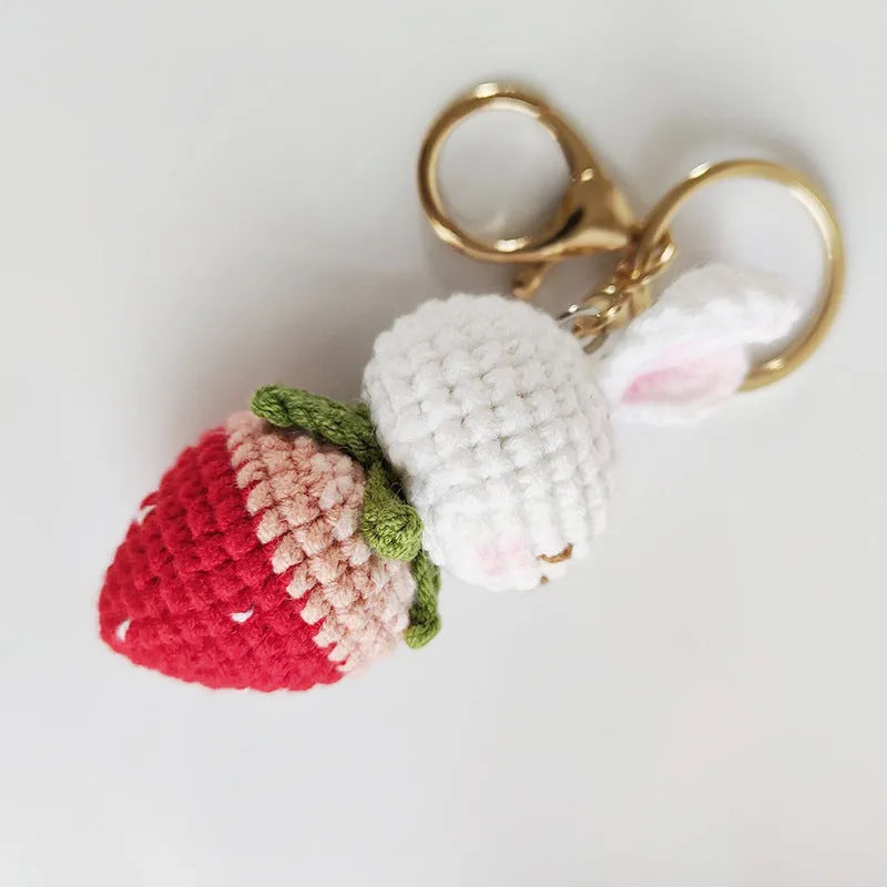 White hand-woven wire pendant showing a rabbit and strawberry design with an attached metal key.