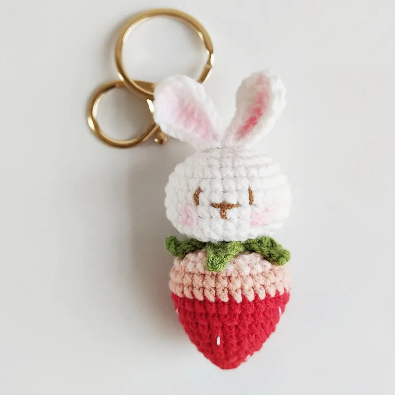 White hand-woven wire pendant showing a rabbit and strawberry design with an attached metal key.