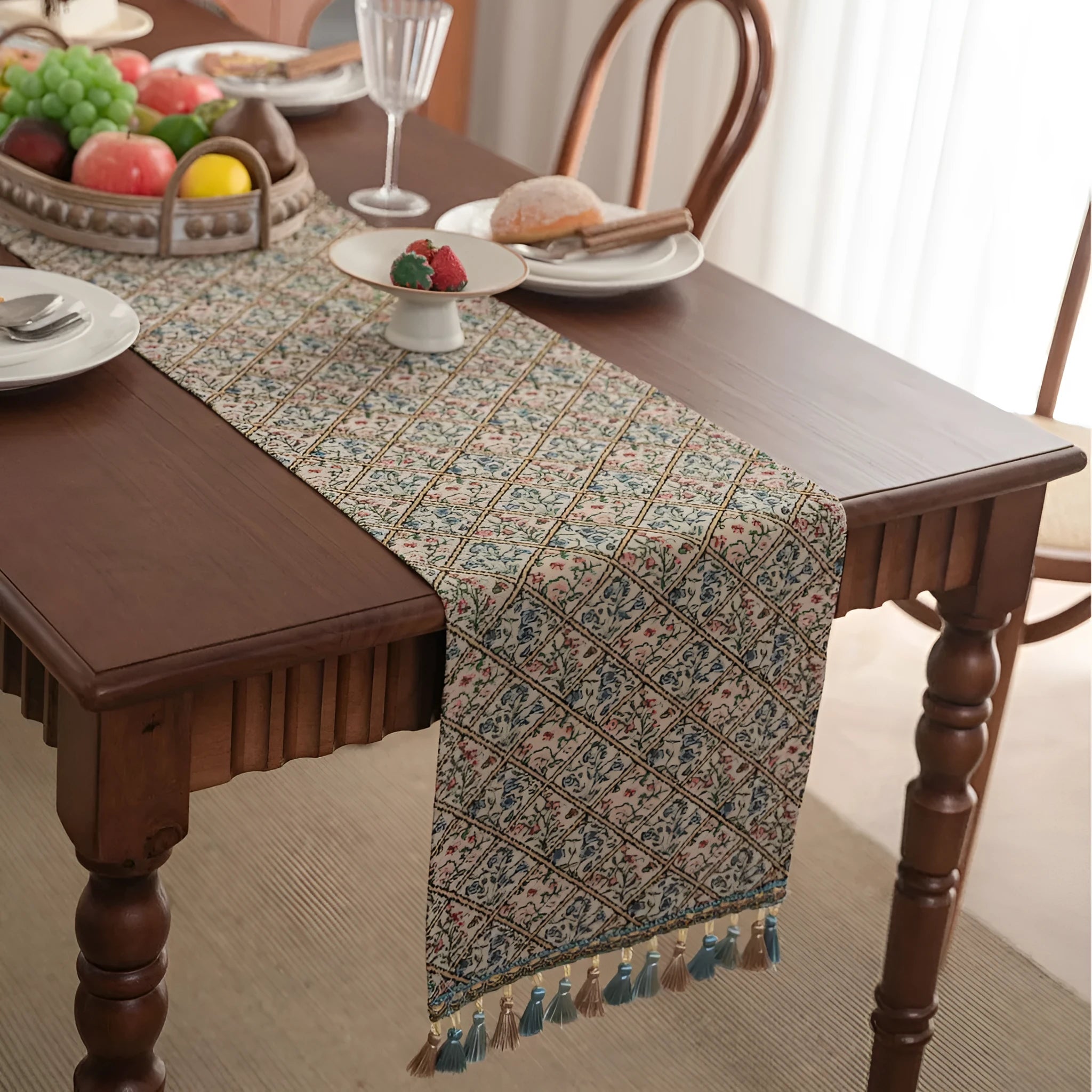 Dark blue jacquard table runner with bouquet pattern and tassels laid on a wooden dining table.