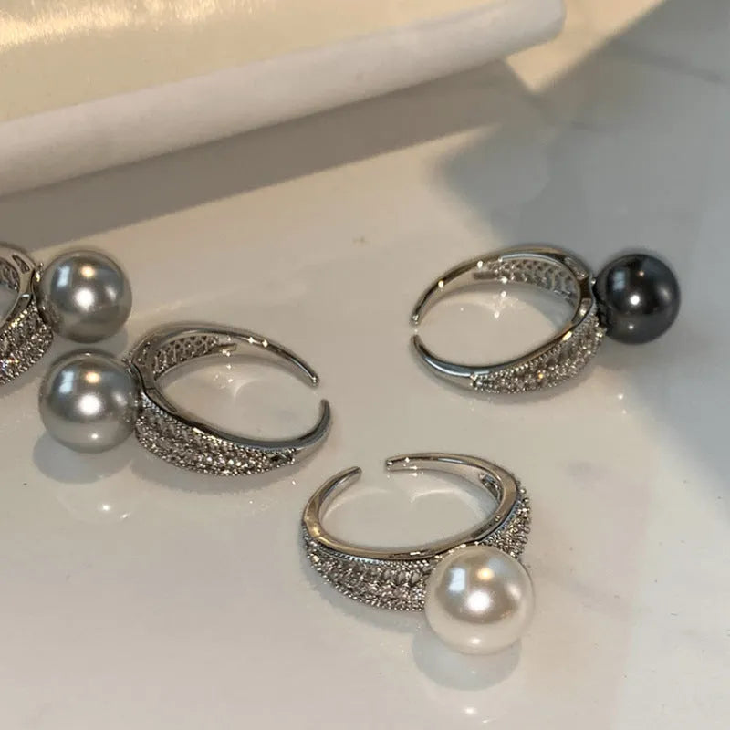 Geometric copper ring with black pearl and adjustable opening on a female index finger.