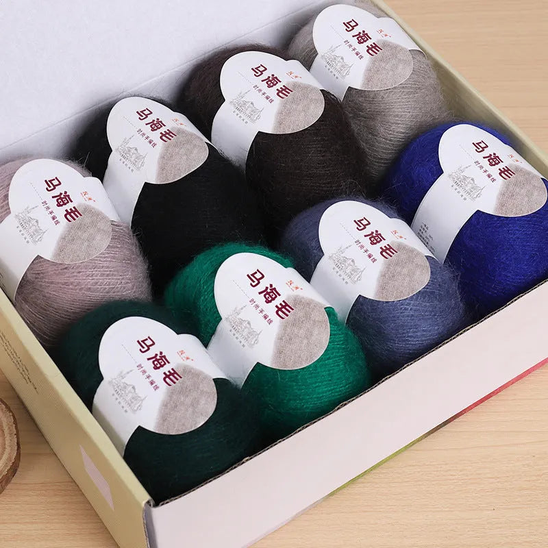 A ball of mohair yarn in a selected colour next to a hand-woven scarf example, showcasing the DIY kit.