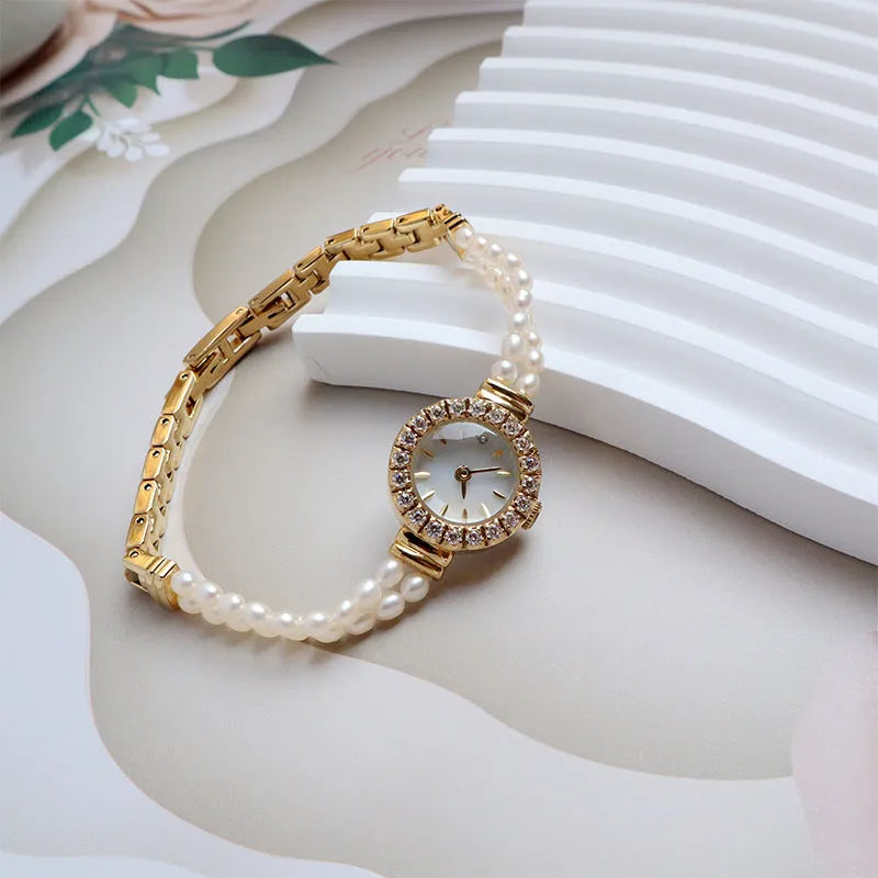 Women's light gold bracelet watch with natural freshwater pearls on a stainless steel strap, showing the 18mm round dial.